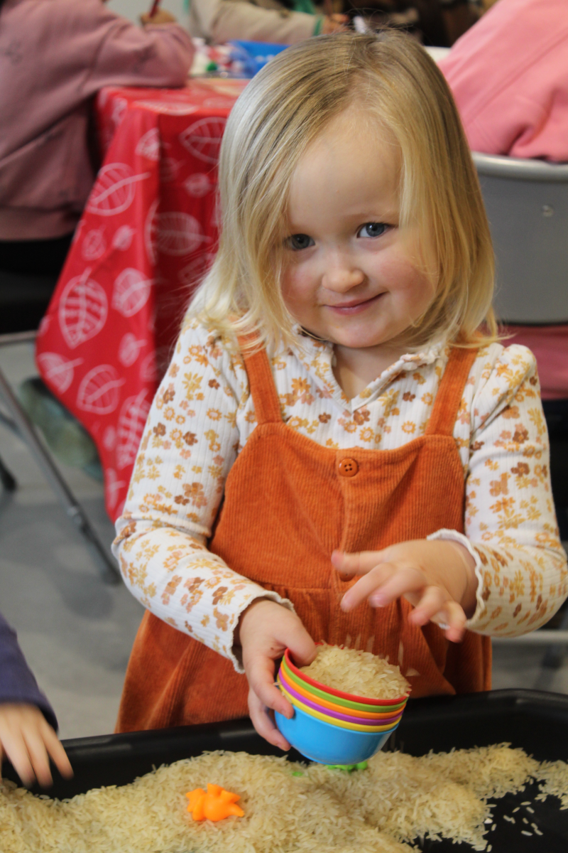 picture of a young blonde girl smiling and playing with rice